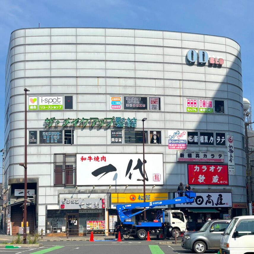 i-spot 鶴瀬駅西口店が入る「OD BLD（ODビル）」の外観。4階の窓に「i-spot 総合リユースショップ」の看板が見える。1階に飲食店などが並ぶ、丸みを帯びたグレーの大きなビル。